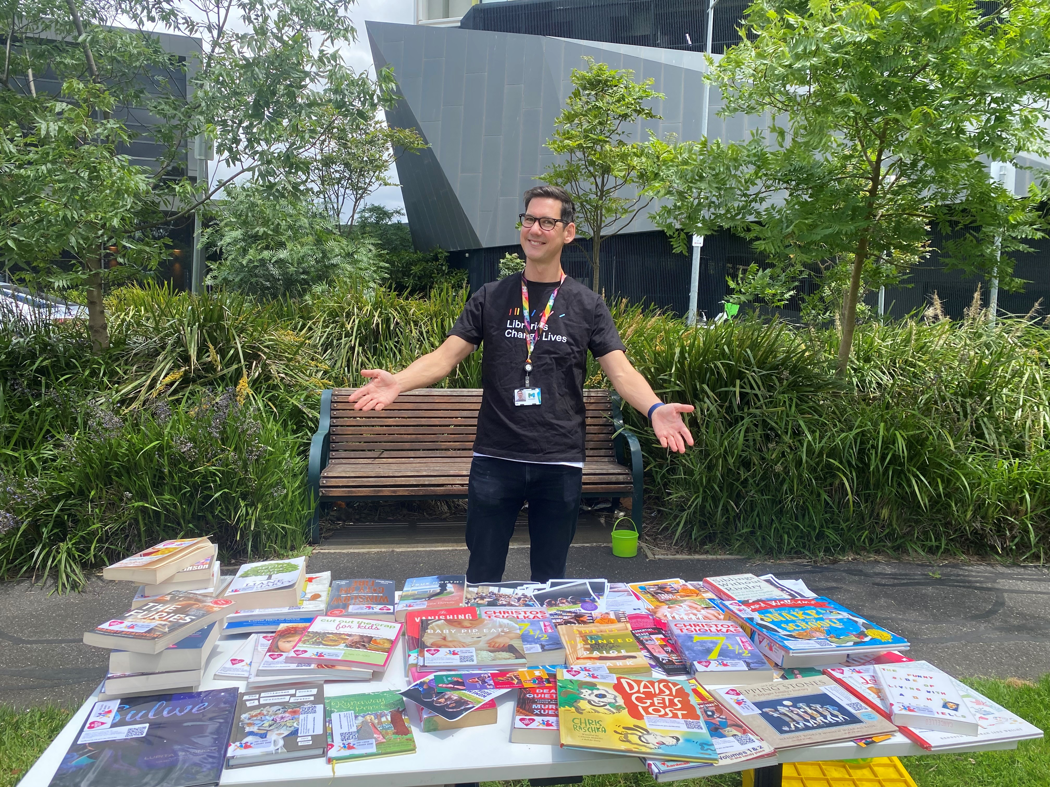 a librarian standing next to a table full of children's resources in a promotional stance
